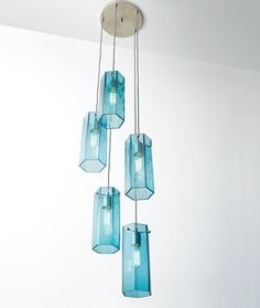 five blue glass vases hanging from a ceiling fixture in a room with white walls