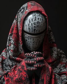 a person wearing a black and red outfit with writing on it's face, in front of a dark background