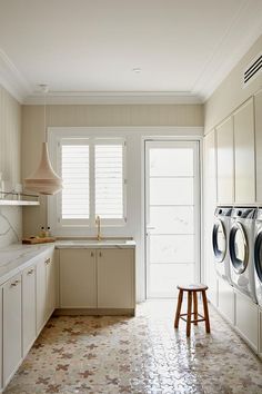 a washer and dryer in a clean white kitchen with tile flooring on the floor