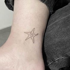 a small star tattoo on the ankle that is black and white, with an outline