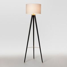 a black tripod floor lamp with a white shade