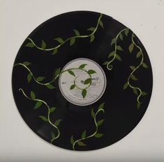 a black record with green leaves on the front and back side, in a white frame