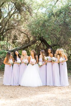 a group of bridesmaids standing together in front of trees