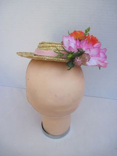 "* A cute mini boater hat has been trimmed out with Easter in mind. Hot pink and vibrant orange flowers complement the carrots off to the side making it a fun and festive hat to wear to any Easter event. * Designed on a 8.0\" diameter round straw hat with an elastic band on the inside. * Designed to look airy and light it would be perfect for a ladies luncheon, charity event or fashion show. * Fun to wear to any Easter Festival or Parade, Egg Hunt, Easter Dinner, Tea or Garden Party, Derby Event Pink Boater Hat For Garden Party, Pink Brimmed Costume Hat For Spring, Pink Brimmed Spring Costume Hat, Spring Pink Brimmed Costume Hat, Retro Pink Summer Hat, Fun Brimmed Summer Costume Hats, Whimsical Flower-shaped Mini Hats For Garden Party, Fitted Orange Mini Hats For Summer, Adjustable Orange Costume Hats And Headpieces For Summer