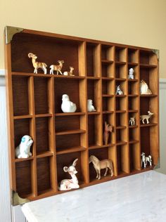 a wooden shelf filled with figurines on top of a white counter next to a wall