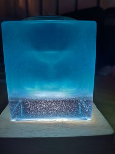 an ice block sitting on top of a wooden table next to a wall with lights in it