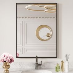 a bathroom sink with a mirror above it and pink flowers in vases on the counter