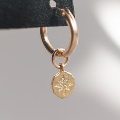 The Oriana gold huggie hoop earrings are a beautiful, delicate addition to anyone's accessory game. The hoops are approx. 15mm and gold filled, suitable for sensitive skin. The charms are approx. 8mm and gold vermeil with a brushed finish, and a stamped star is accented with a tiny CZ stone. 14k gold filled hoops, suitable for sensitive skin Brushed gold vermeil starburst charm Dainty 14k Yellow Gold Filled Huggie Earrings, Everyday 14k Gold Jewelry With Star Charm, 14k Gold Filled Huggie Jewelry With Dangling Charms, Dainty Recycled Gold Huggie Earrings, Recycled Gold Huggie Earrings, Gold Huggie Earrings With Dangling Charms For Everyday, Everyday Gold Huggie Earrings With Dangling Charms, 14k Gold-filled Yellow Gold Star Charm Jewelry, 14k Yellow Gold Filled Dangle Huggie Earrings