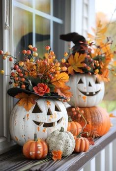 two pumpkins decorated with flowers and leaves on a window sill