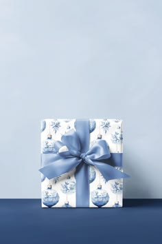 a blue and white gift box with a bow on it sitting on a table next to a wall