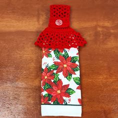 a crocheted red poinsettia and white towel on a wooden table