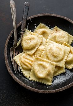 a plate full of ravioli on a black surface with a fork next to it