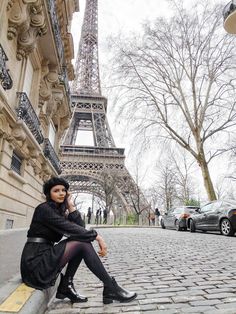 a woman sitting on the ground in front of the eiffel tower