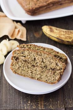 two slices of banana bread sitting on top of a white plate next to some bananas