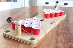 a wooden tray with red cups on it