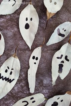 some white leaves with black faces and eyes painted on them are arranged in the shape of ghostes