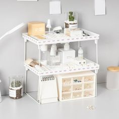 a white shelf filled with lots of items on top of a table next to a lamp