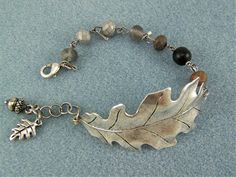 A warm oxidized silver oak leaf is curved to fit the wrist. Assorted silver shades of glass rondelle beads form the bracelet. Tiny silver-plated oak leaf and acorn charms accent the lobster clasp closure. The extension chain makes the bracelet adjust from 6 3/4" to 8". If you need a longer extension, please let me know. This bracelet features a beautiful oxidized silver finished (metal) oak leaf with warm toned beads and silver charms. - 6 3/4" (17cm) total chain bracelet - oak leaf measures app Silver Leaf Bracelet, Cuff Bracelet Silver, Crystal Teardrop Earrings, Silver Oak, Purple Pansy, Beaded Leaf, Beaded Cuff Bracelet, Leaf Bracelet, Beaded Cuff