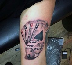 a tattoo on the arm of a man with playing cards and dices in it