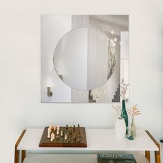 a white table with a chess board and vase on it in front of a mirror