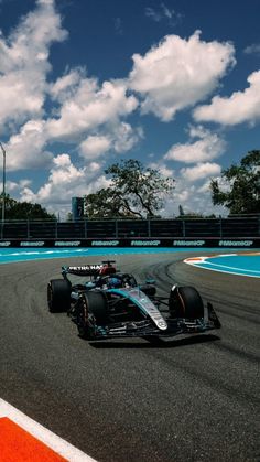 two racing cars on a race track with blue sky and clouds in the back ground