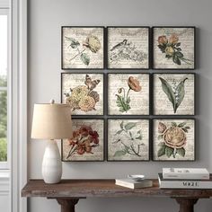 a table with some books and a lamp on it next to a wall mounted art piece