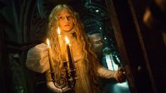 a woman with long blonde hair holding two candles