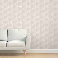 a white couch sitting in front of a wall with a plant pattern on it's side