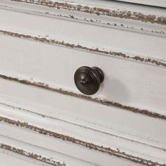 an old dresser with white paint and brown knobs on the drawer handles is shown