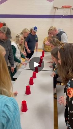 a group of people standing around a long table with red cups on top of it