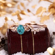 two wedding rings sitting on top of a wooden box in the snow with gold leaves around them