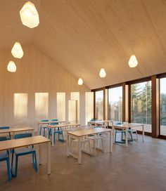 an empty classroom with desks and chairs in front of large glass windows on the wall