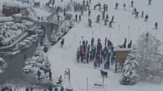 a group of people standing on top of a snow covered slope next to a river