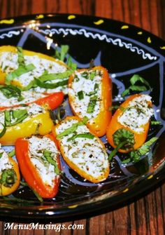 stuffed peppers with cheese and herbs in a black plate on a wooden table, ready to be eaten