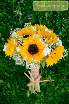 a bouquet of sunflowers and baby's breath sits on the ground in front of some green grass