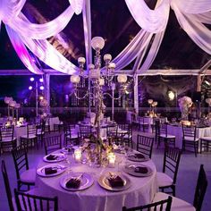 a table set up for an event with white draping and chandeliers