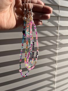 a person holding some kind of multi colored beaded necklace in their left hand,