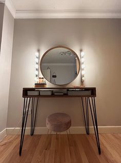 a dressing table with a mirror, stool and lights on the wall in front of it