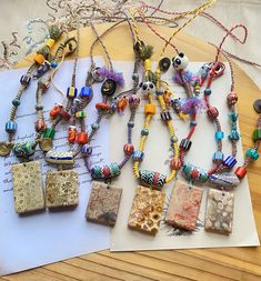 several necklaces are laid out on top of a piece of paper and some beads