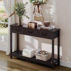 a black console table with two drawers and some plants on the shelf next to it