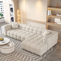 a living room with a large sectional couch and coffee table in the center, along with shelves filled with books