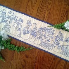 a cross - stitch christmas scene on a table runner