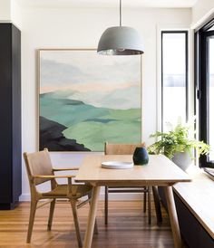 a dining room table with two chairs and a large painting on the wall behind it