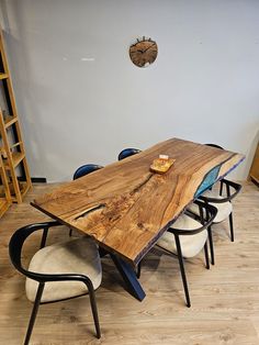 a wooden table sitting on top of a hard wood floor next to two white chairs