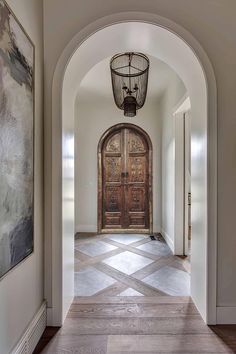 an archway leading to a large wooden door in a home with hardwood floors and white walls