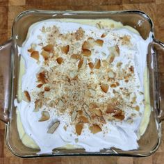 a dish filled with cream and nuts on top of a wooden table next to a knife