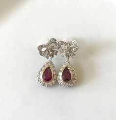 Metal: 14kt White Gold Stone: Diamond And Ruby Shape: Round And Pear-shape Ruby Weight : 1.00 ctw Diamond Weight: .52 ctw Type Of Backing: Post Weight of entire piece: 5.60 grams Dimensions of Earrings From Top To Bottom: 24.22mm Customizable: We can custom make these earrings (and its matching necklace) with any gems and metals of your choice. Please inquire if interested. Matching Necklace: https://www.etsy.com/listing/549448744/vintage-style-14k-white-gold-ruby-and?ref=shop_home_active_2 Luxury Hallmarked Pear-shaped Diamond Earrings, Platinum Pear-shaped Diamond Earrings For Formal Occasions, Ruby Gemstone Diamond Earrings For Formal Occasions, Formal Ruby Gemstone Diamond Earrings, Wedding Ruby Earrings With Brilliant Cut, Ruby Earrings With Brilliant Cut For Wedding, Hallmarked Pear-shaped Diamond Earrings For Anniversary, Pear-shaped Hallmarked Diamond Earrings For Anniversary, Pear-shaped Diamond Earrings For Formal Events