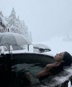 a woman sitting in a hot tub covered in snow