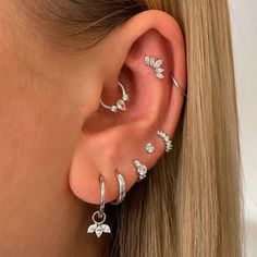 a close up of a person wearing ear piercings with flowers and leaves on them