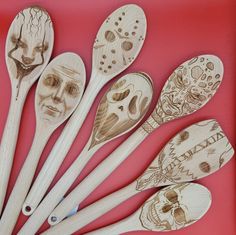 wooden spoons with carved faces on them are lined up against a red background,